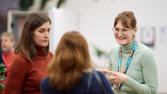 Menna Clarke standing with people at an event and smiling. 