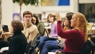 A Skoll Centre event in the Nest, as someone is raising their hand. 