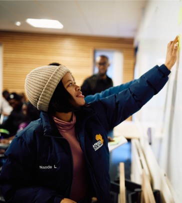 An AfOx student reaching up to a whiteboard.