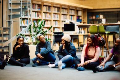 A goup of AfOx students talking with one another on the floor at Egrove Park at SBS.