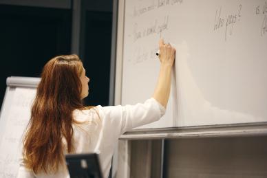 Juliane Reinecke writing on a white board wearing a white shirt.