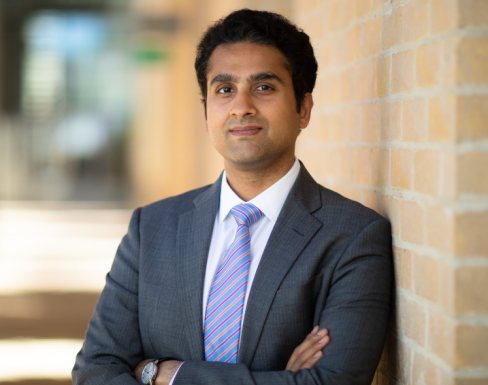 Akshay Mangla Akshay Mangla standing in the SBS hallway wearing a grey suit and smiling.