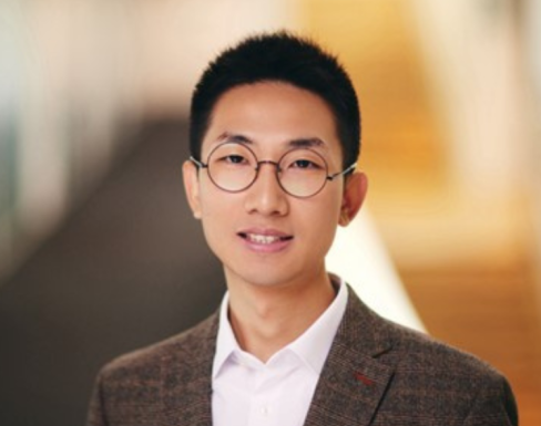 Cheng Li Cheng Li standing in the SBS hallway wearing a brown suit.