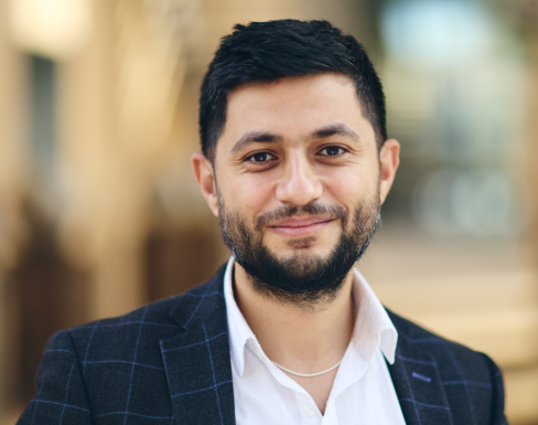 Ammar Azzouz Closeup shot of Ammar in a white shirt and navy blazer, smiling at the camera