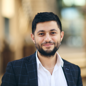 Ammar Azzouz Closeup shot of Ammar in a white shirt and navy blazer, smiling at the camera